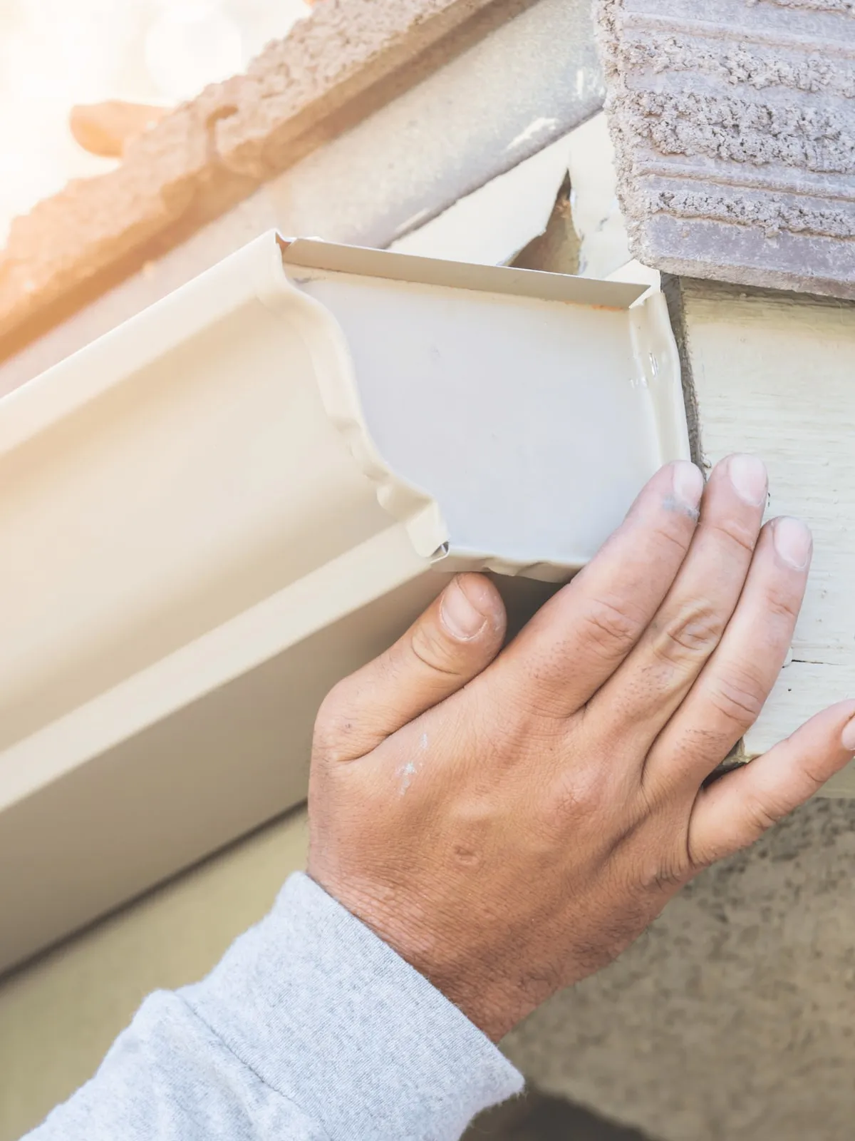 Installer fitting a seamless gutter end cap to the fascia