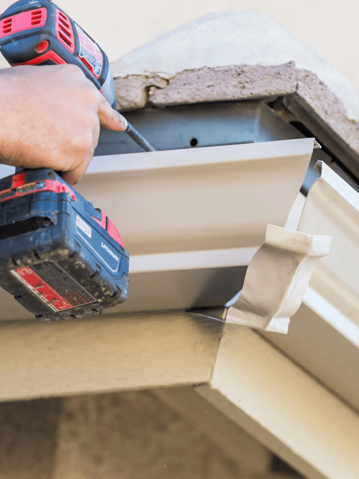 Installer securing a gutter corner with a power drill