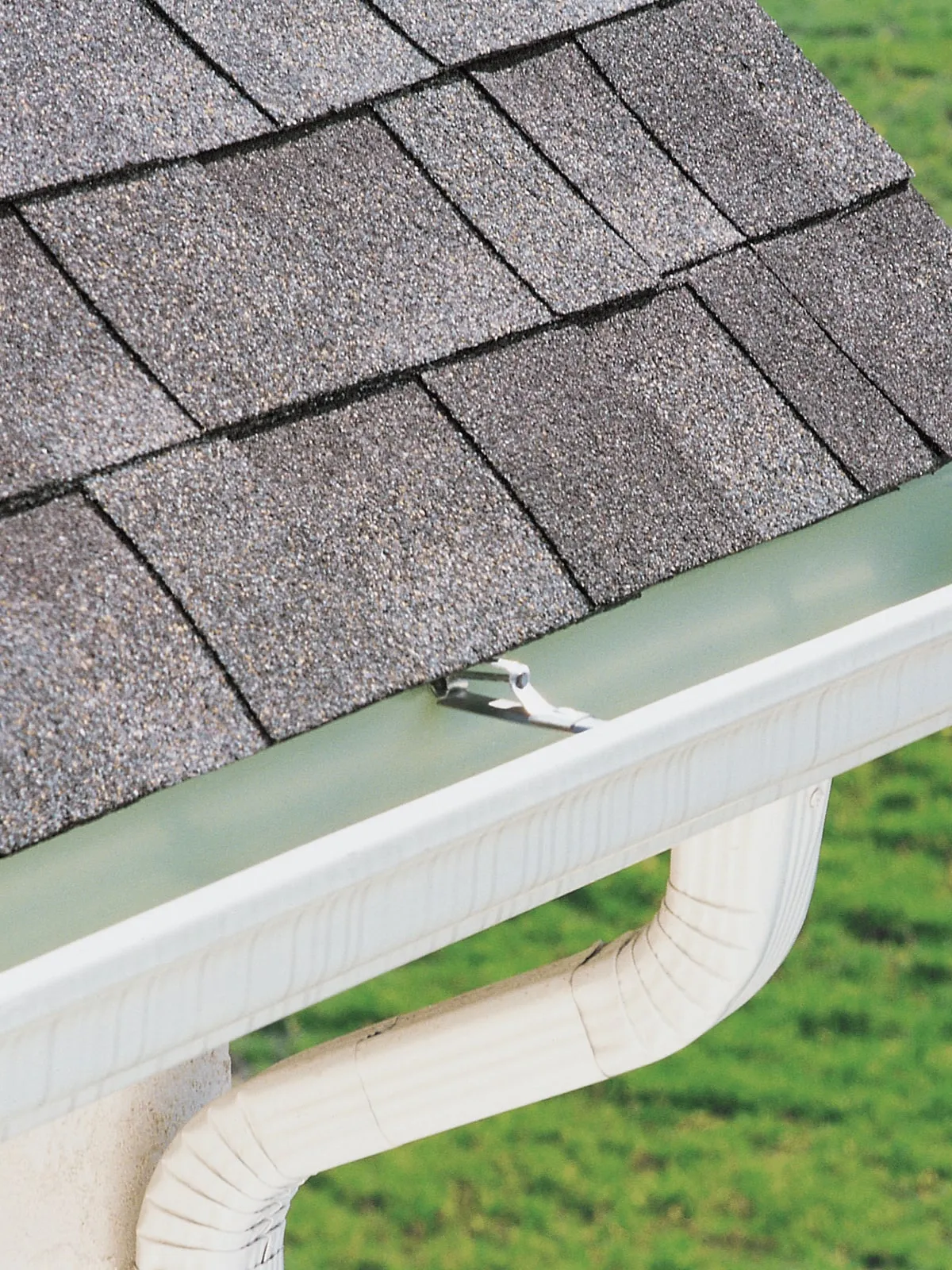 New gutter and downspout below an asphalt shingle roof