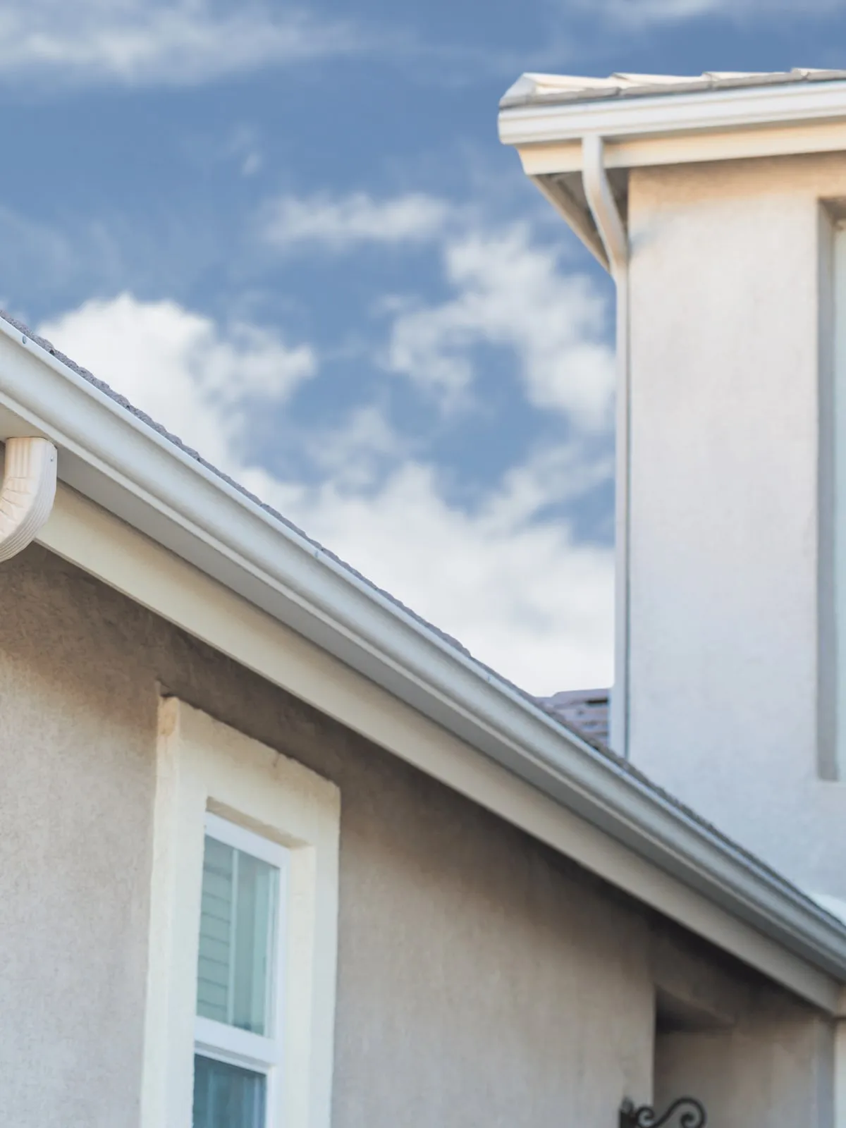 White seamless gutters on a two-story stucco home