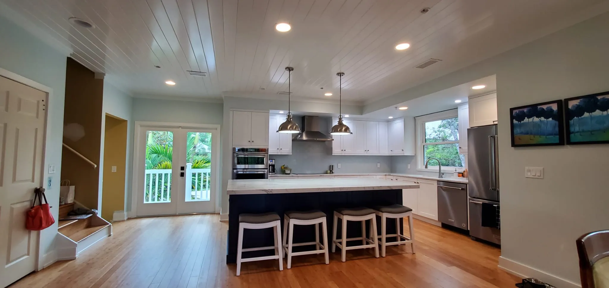 Open kitchen with white cabinets, navy island and wood floors
