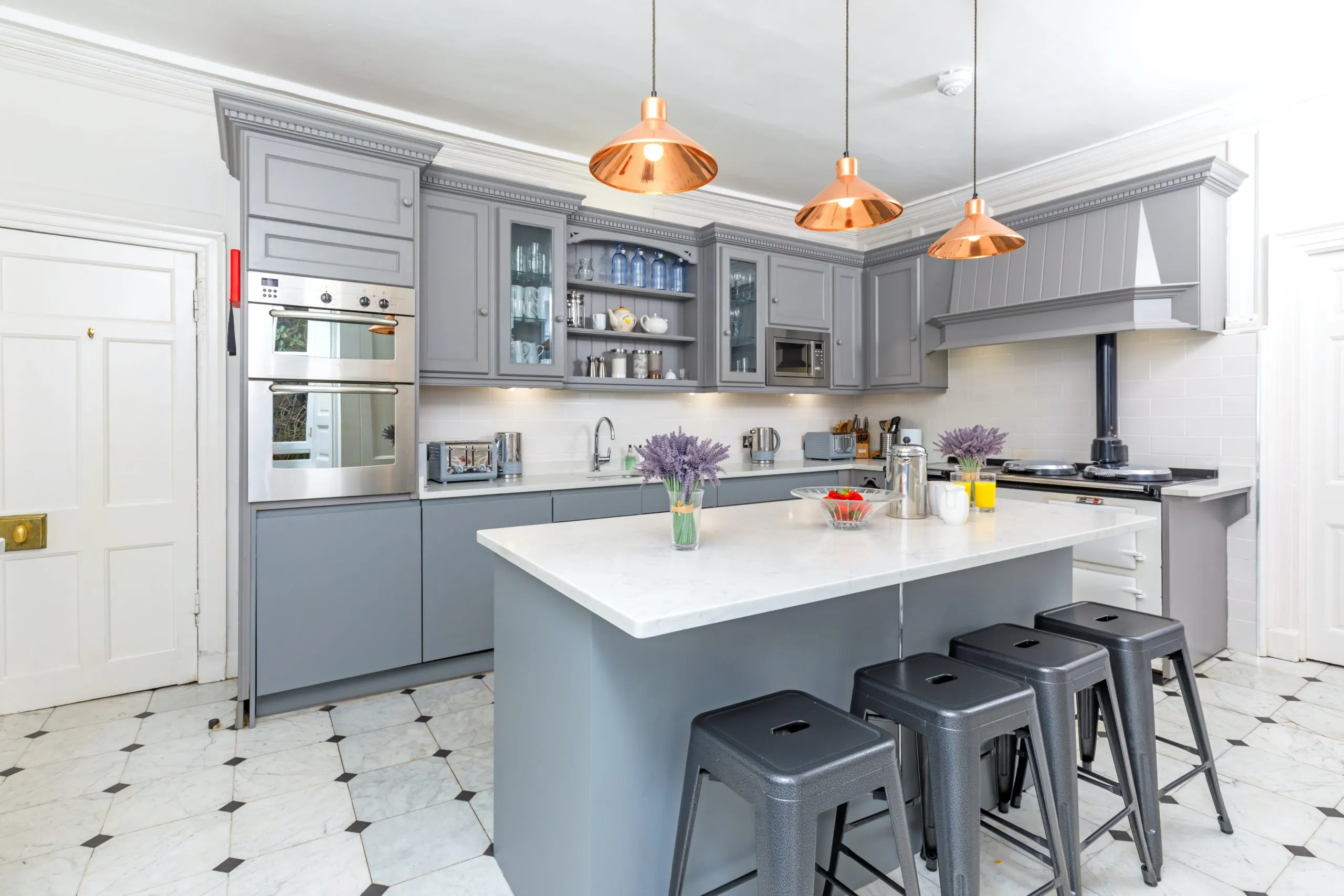 Gray kitchen with copper pendants and white island