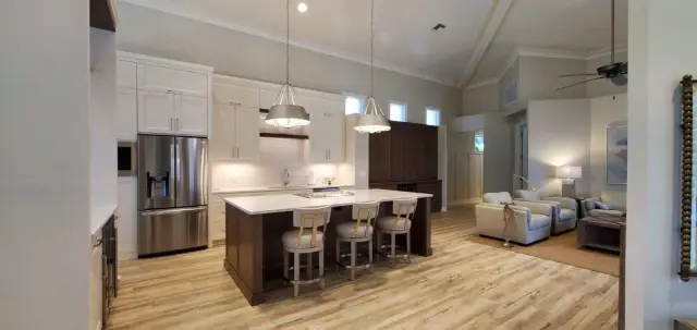 Open-concept kitchen with dark island and white cabinets